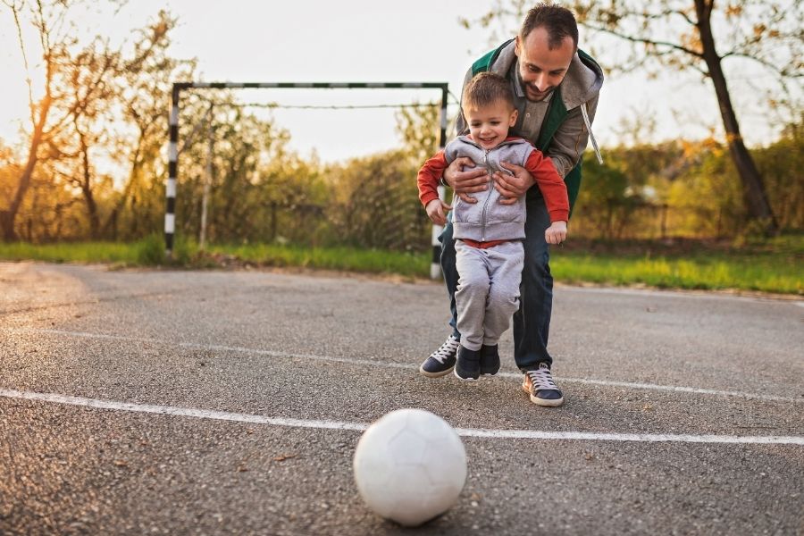Padre con hijo pequeño jugando al fútbol